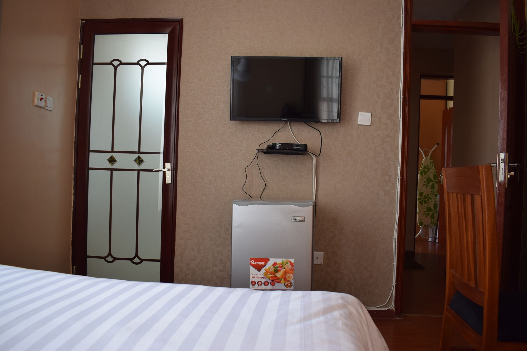 Une chambre d’hôtel équipée d’un lit, d’un téléviseur fixé au mur et d’un mini-bar.