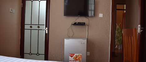 Une chambre d’hôtel équipée d’un lit, d’un téléviseur fixé au mur et d’un mini-bar.