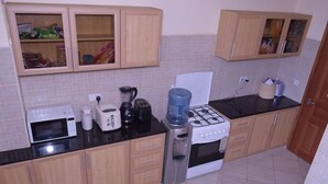 Uma cozinha equipada com fogão, micro-ondas, torradeira e armários.