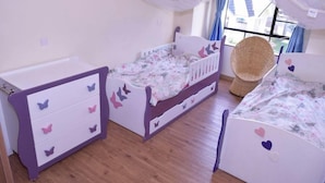 Quarto de criança com cama, cômoda e cadeira.