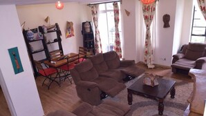 Uma sala de estar com sofás marrons, uma mesa de centro de madeira e uma mesa de jantar vermelha.
