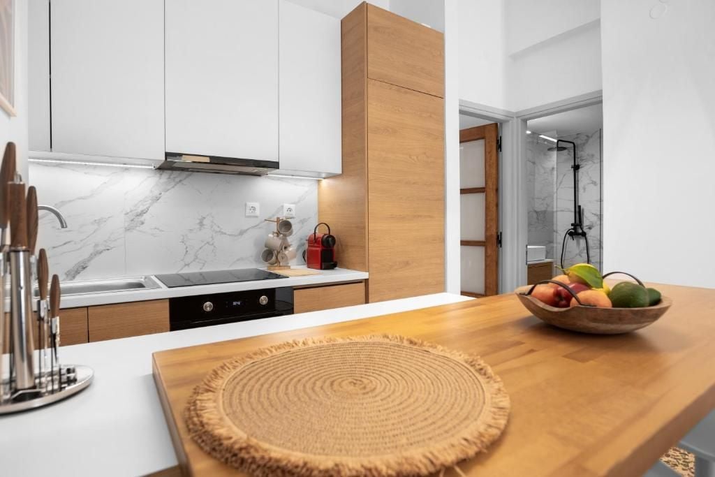 A modern kitchen with white cabinets, a wooden countertop, and a fruit bowl.