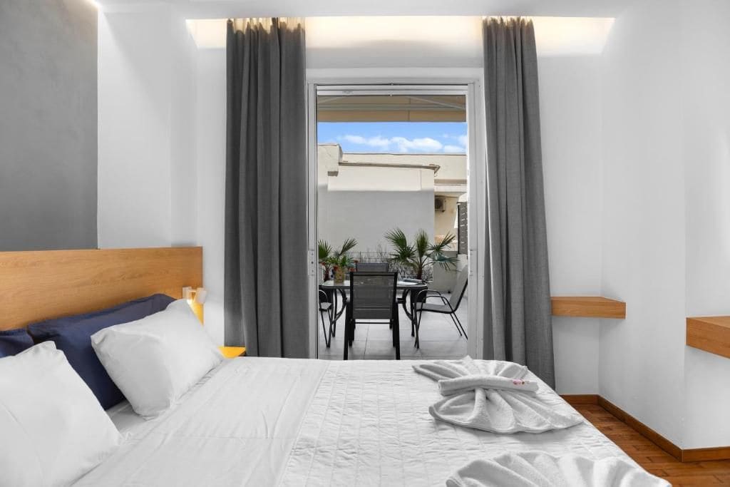 A hotel room with a bed, a desk, and a view of the outside.