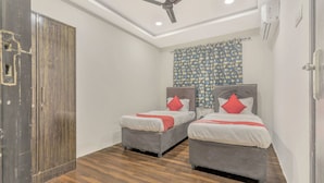 Habitación de hotel con dos camas, un ventilador de techo y una cortina estampada.
