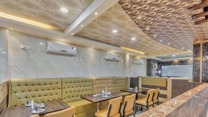 Un interior de restaurante con mostrador de mármol, asientos acolchados y unidades de aire acondicionado.
