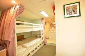 Habitació amb lliteres, un escriptori petit, un mirall i un quadre al mur.