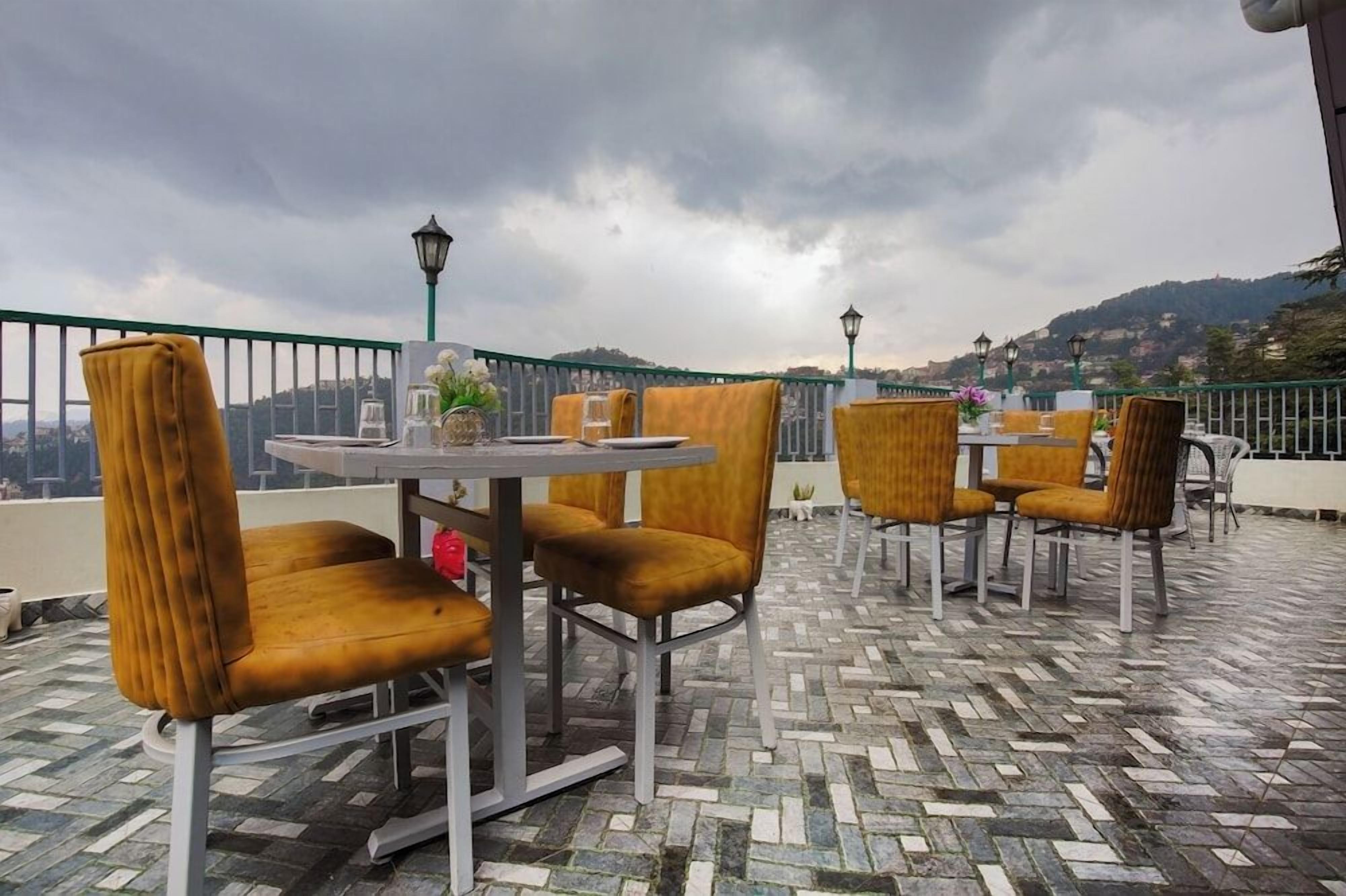 An outdoor seating area with round tables and chairs, a patterned floor, and a view of a cityscape.