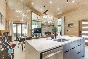Una cocina moderna con una isla grande, electrodomésticos integrados y una chimenea de piedra.