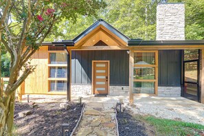 Ein modernes Haus mit einem Steinkamin, Holzverkleidung und einem Steinweg, der zum Eingang führt.