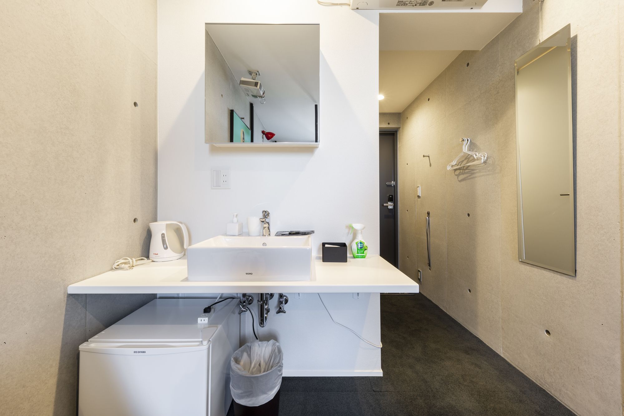 A modern bathroom with a sink, mirror, and a small refrigerator.