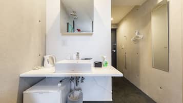 A modern bathroom with a sink, mirror, and a small refrigerator.