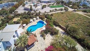 A residential area with a swimming pool, white buildings, and a view of the sea. - Villa Pari Manda (Naxos)