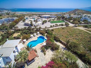 A residential area with a swimming pool, white buildings, and a view of the sea. - Villa Pari Manda (Naxos)