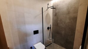 A modern bathroom with a glass-enclosed shower, a toilet, and a trash bin. - Ulmo Collection Ayasaranda (Çeşme)