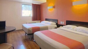 Una habitación de hotel con dos camas, un escritorio y una ventana con cortinas.