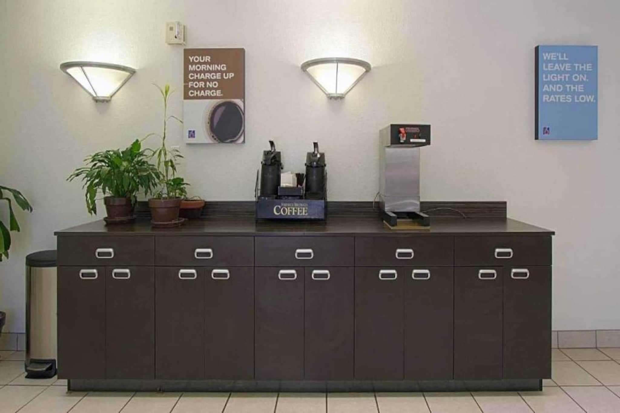 A reception desk with a coffee station, a sign about morning charge, and a sign about leaving the light on.