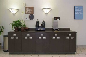 A reception desk with a coffee station, a sign about morning charge, and a sign about leaving the light on.