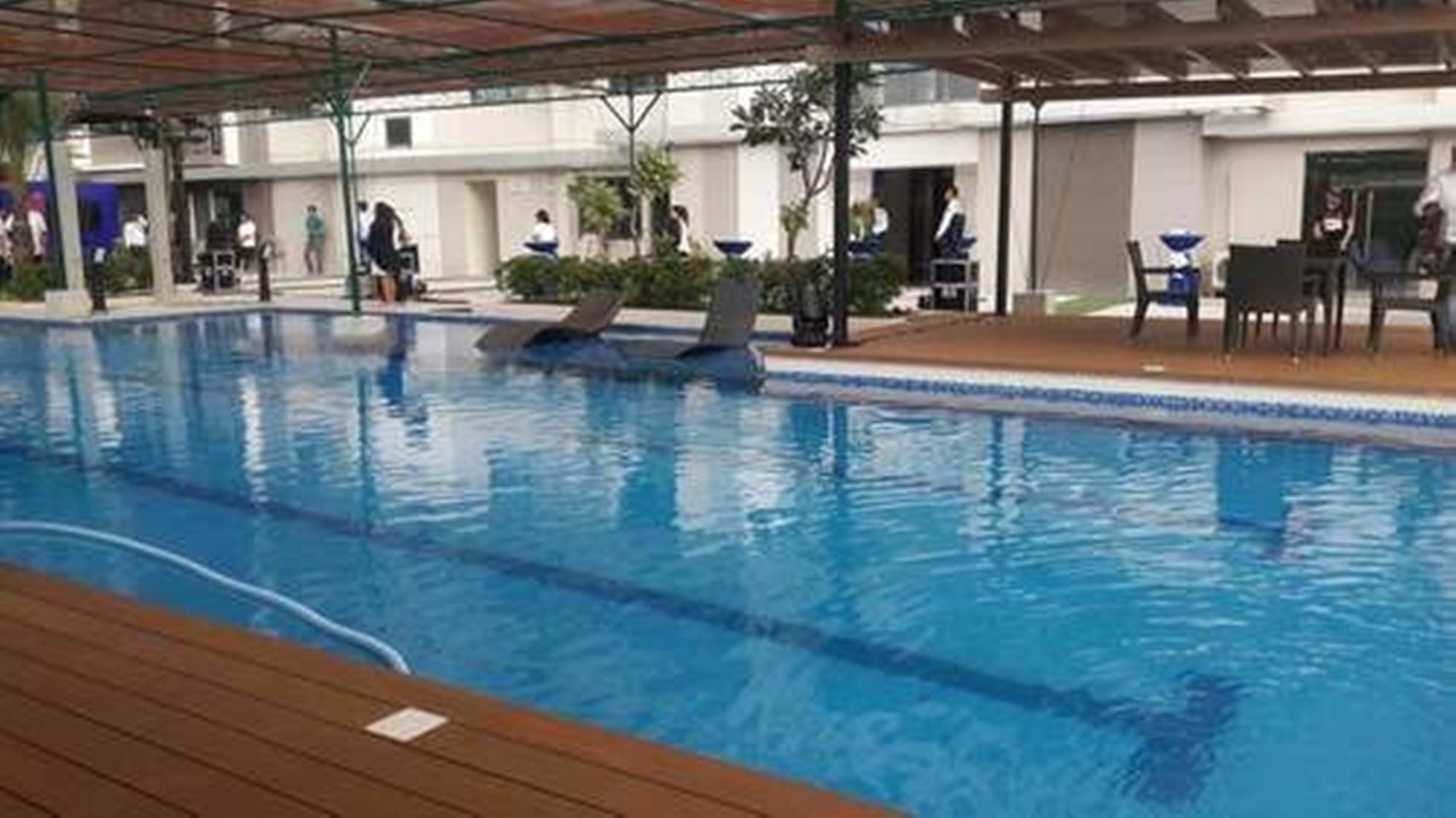An indoor swimming pool with a wooden deck area and a covered seating section.