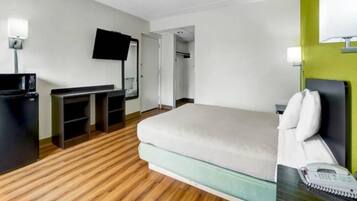A hotel room with a bed, a desk with a computer, a television, and a telephone.