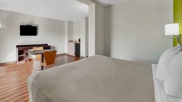 Una camera d'albergo con un letto, una scrivania, una sedia e un televisore appeso al muro.