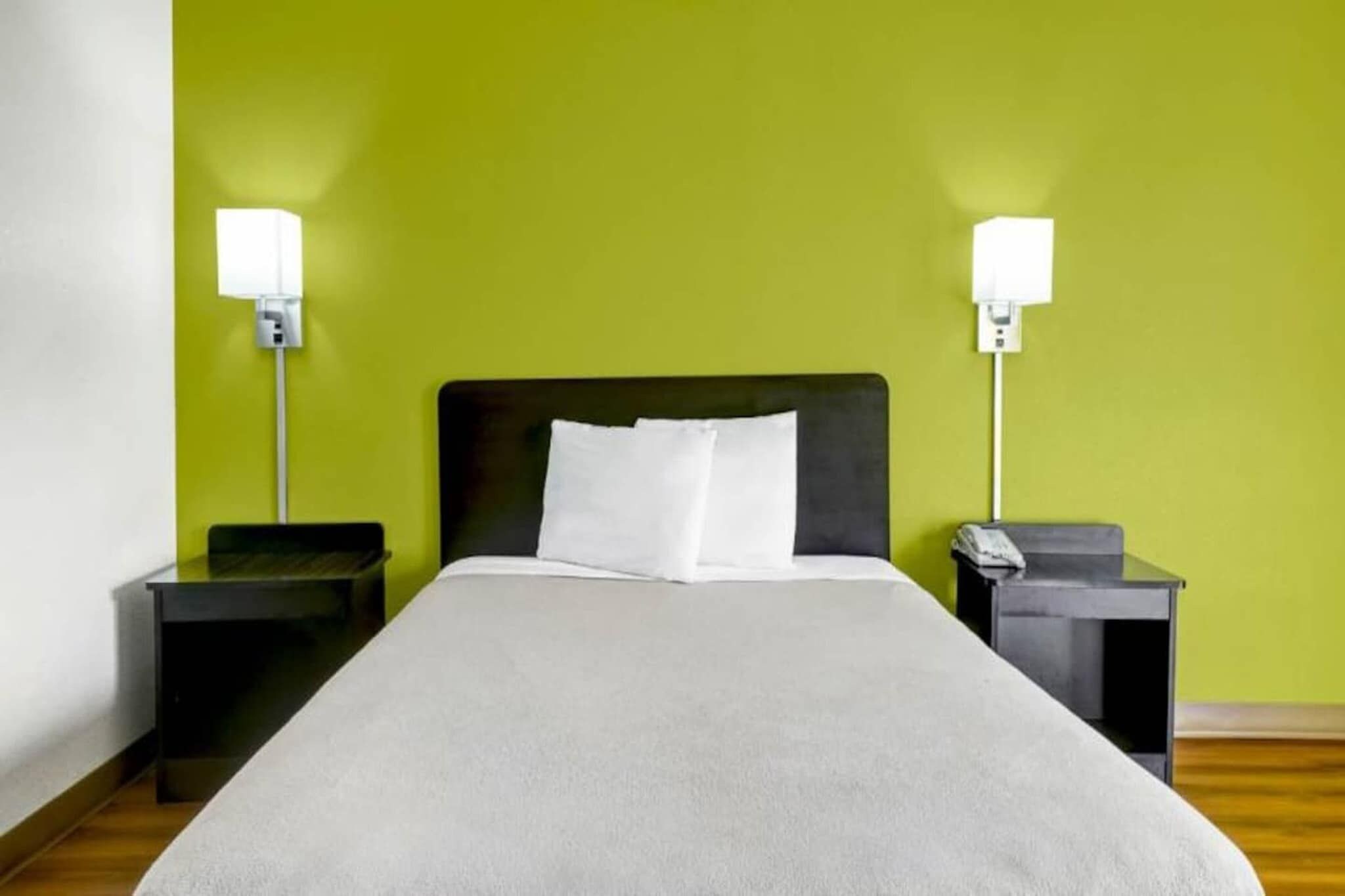 A hotel room with a bed, two bedside tables, and two wall-mounted lamps.