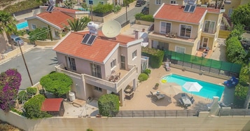 Zona residencial con varias casas, una piscina y paneles solares en los tejados.