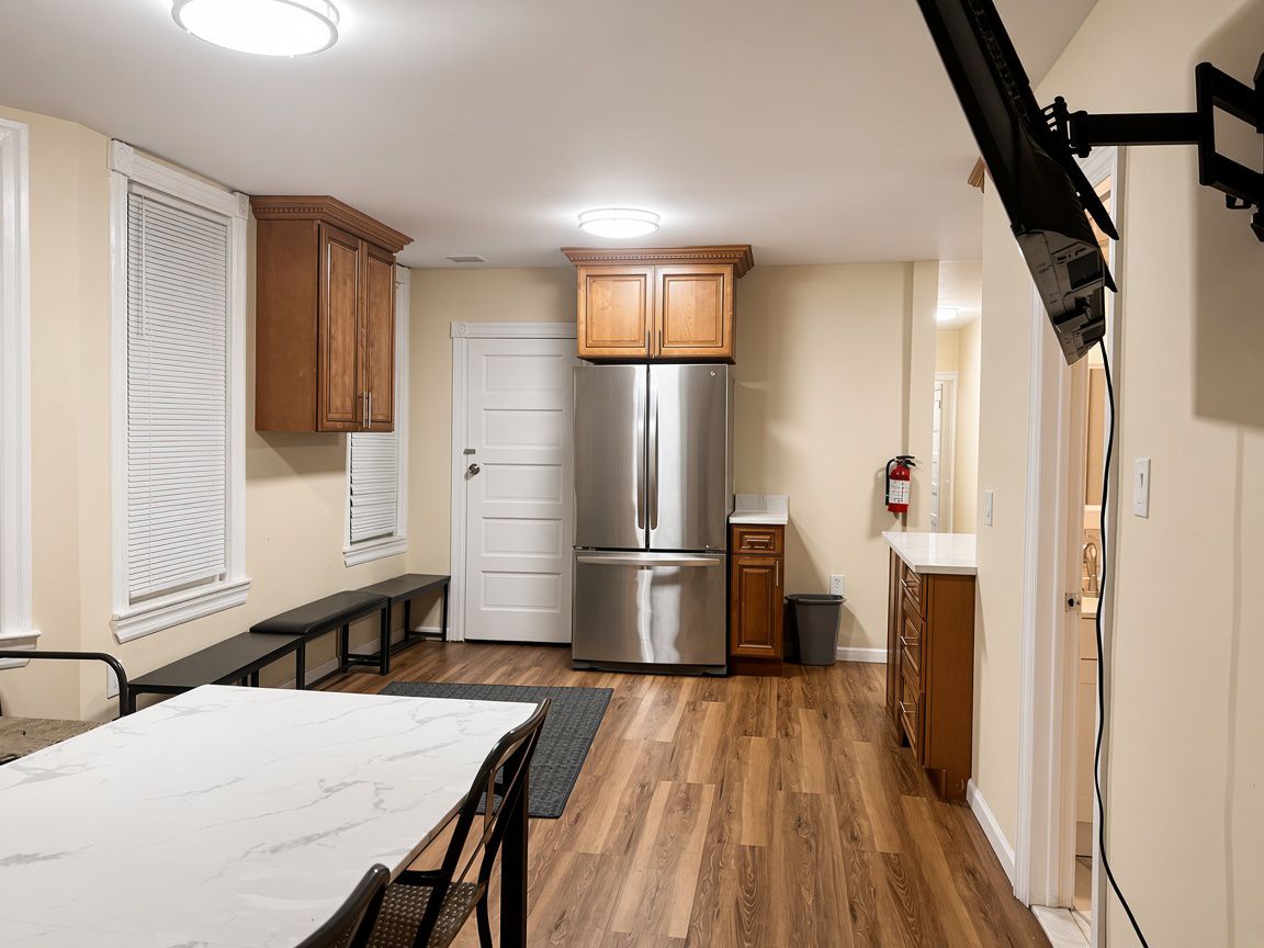 A compact kitchen with a built-in refrigerator, wooden cabinets, and a dining area with a marble table.