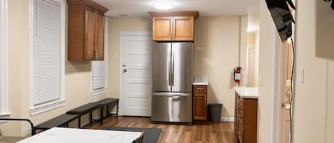 A compact kitchen with a built-in refrigerator, wooden cabinets, and a dining area with a marble table.