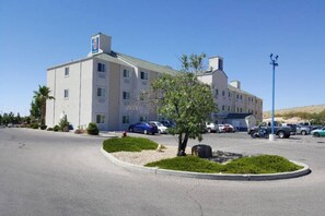 Een hotel met meerdere verdiepingen en een parkeerplaats ervoor.