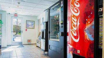 Automaatti, jossa on Coca-Colan logo, uloskäyntikyltti ja ovi, joka johtaa laatoitetulle käytävälle.