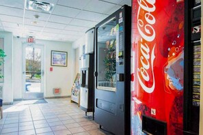 Een automaat met een Coca-Cola logo, een bord met daarop ‘uitgang’ en een deur die leidt naar een gang met betegelde vloer.