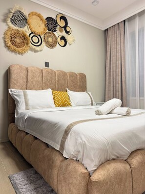 Ett hotellrum med en stor säng, en sänggavel och en dekorativ detalj som hänger på väggen.