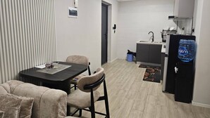 Un espacio habitable compacto con comedor, kitchenette y dispensador de agua.