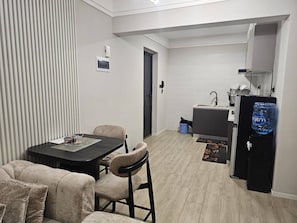 Ett kompakt bostadsutrymme med matplats, ett litet kök och en vattenautomat.
