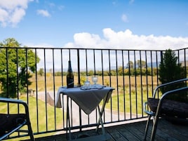 Un balcón con una mesa dispuesta para dos personas, con vistas a un paisaje cubierto de césped.