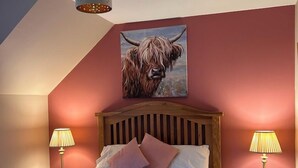 Un dormitorio con una cama de madera, dos lámparas de noche, un candelabro en el techo y un cuadro de una vaca en la pared.