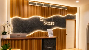 A reception desk with a Lenovo laptop, a sign reading 'The Sense,' and a plant.