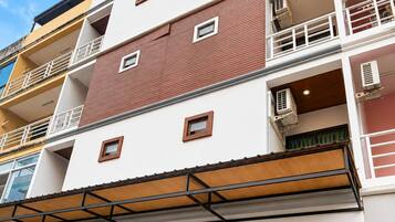 Un edificio de varios pisos con una cafetería en la planta baja y terraza.