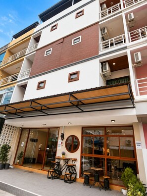 A multi-story building with a ground-level cafe featuring outdoor seating. - The Sense Hotel Patong (Patong)
