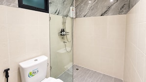 A modern bathroom with a glass-enclosed shower, a toilet with a water-saving label, and a mounted TV.