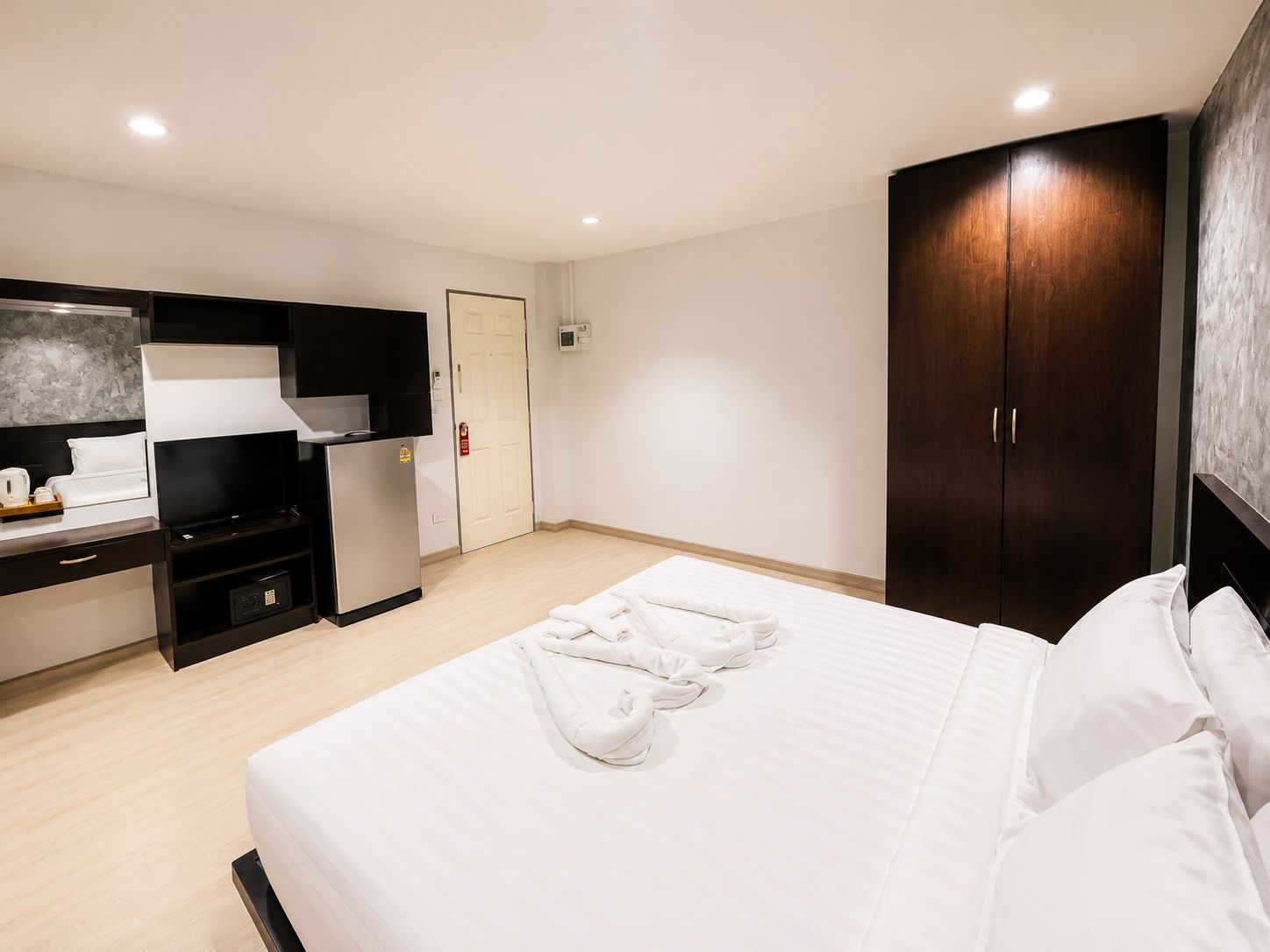 Una habitación de hotel con cama, escritorio con televisor, minibar y armario.