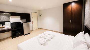 Una habitación de hotel con cama, escritorio con televisor, minibar y armario.