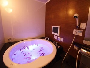 Une salle de bain dotée d’une grande baignoire, d’un pommeau de douche à main et d’un panneau de commande fixé au mur.