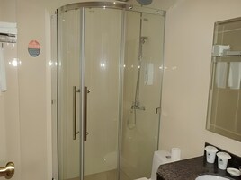 Casa de banho moderna com cabine de duche em vidro, lavatório com bancada de mármore e espelho sobre o lavatório.