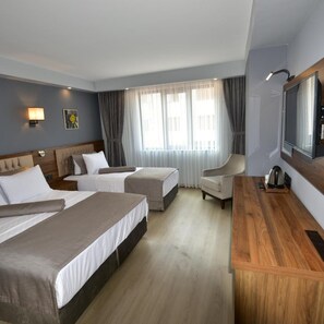 Habitación de hotel con dos camas, un escritorio, una silla, un televisor y una ventana con cortinas.