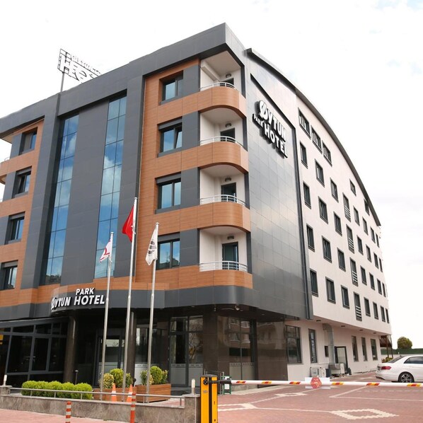 Un hotel de varios pisos con diseño moderno, que destaca un letrero grande que dice 'Park Hotel' y una entrada visible.