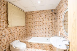 A bathroom with a toilet, a bathtub, and a sink. - Nawarah Altakhassusi 6 (Riyadh)