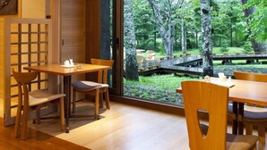 Un comedor con mobiliario de madera y vistas a un jardín a través de un ventanal amplio.