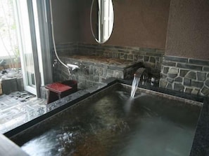 Spa-område med jacuzzi, stenvæg og spejl.