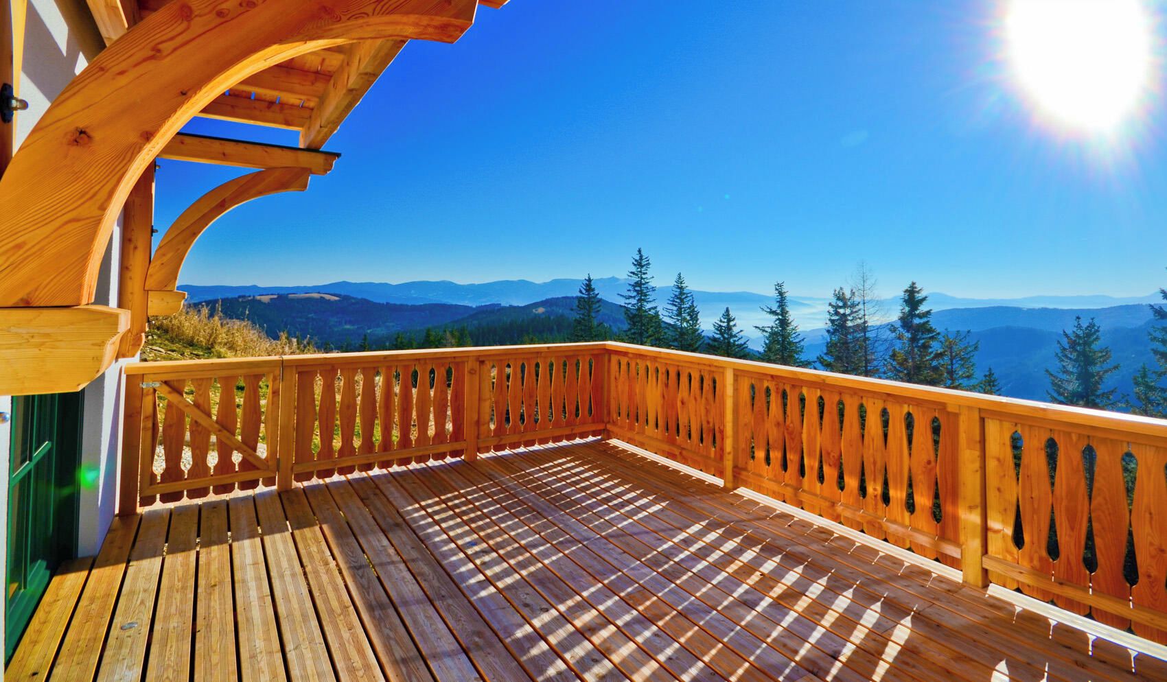 A wooden deck with a view of mountains and trees.